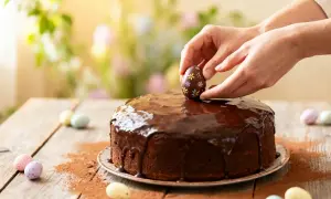 Un délicieux dessert de Pâques facile : un gâteau au chocolat glacé, décoré d'un œuf en chocolat fleuri.