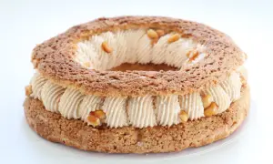 Un Paris-Brest rond, garni d'une crème onctueuse et parsemé de morceaux de praliné cacahuète croquant.