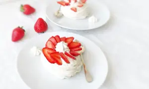 Deux pavlovas ornés de fraises et de crème fouettée, une touche de curd mangue passion pour l'exotisme.