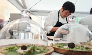 Chef prépare des mets délicats sous cloche, peut-être inspirés par le vignoble de Meursault.