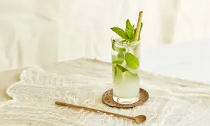 Un verre de nom de cocktail rafraîchissant avec de la menthe et de la glace, sur une nappe en dentelle.