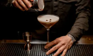 Un barman termine la préparation du cocktail du moment, saupoudrant des grains de café sur la mousse onctueuse d'un verre à martini.