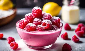 Un délicieux curd framboise, saupoudré de sucre glace, avec des framboises fraîches et un citron en arrière-plan.