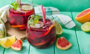 Deux verres de sangria rouge vif, garnis de fruits et de menthe, prêts à être dégustés. Le vin pour sangria est parfait pour les journées chaudes.