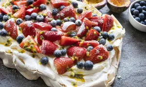 Pavlova recette : meringue aérienne garnie de crème fouettée, fraises, myrtilles et fruits de la passion. Un délice !