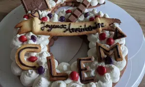 Gâteau décoré de crème fouettée, biscuits en forme de lettres formant "CLEM", chocolats et bonbons. Quelle crème pour recouvrir un gâteau, celle-ci est parfaite !