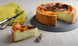 Un flan pâtissier onctueux sur une pâte feuilletée ou brisée dorée, avec une part coupée. Un délice à déguster !