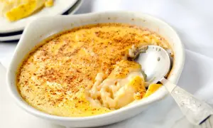 Un délicieux oeuf au lait crémeux, saupoudré de cannelle, est servi dans un ramequin blanc. Une cuillère en argent est enfoncée dans le dessert.
