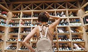 Une femme choisit une bouteille dans une cave à vin, un paradis pour tout négociant en vin.