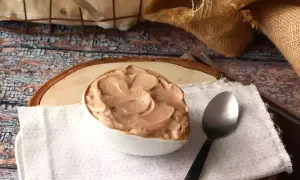 Une cuillère attend patiemment à côté d'un bol rempli d'une onctueuse ganache Nutella, prête à être dégustée.