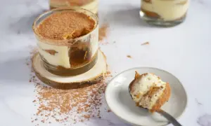 Délicieux tiramisu, un dessert sans cuisson, servi dans des verres, saupoudré de cacao. Une cuillère en est prête à être dégustée.