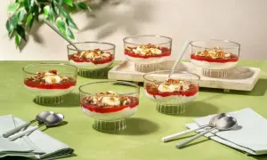 Six coupes de dessert aux graines de chia, garnies de compote de fraises, de rondelles de banane et de noix, parfaites pour un goûter.