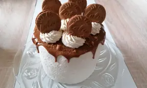Gâteau blanc crémeux, nappé de chocolat fondant et décoré de biscuits spéculoos et de crème fouettée.