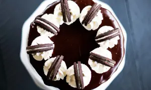 Gâteau au chocolat glacé, décoré de crème fouettée et de biscuits Oreo. Un délice pour les amateurs de layer cake Oreo.