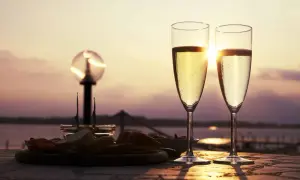 Deux flûtes de ratafia de Champagne pétillant, servies avec des amuse-bouches au coucher du soleil. Parfait pour savoir comment le boire.