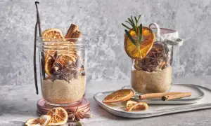 Ingrédients pour une recette de vin chaud : sucre, bâtons de cannelle, anis étoilé, cardamome, orange séchée et vanille dans des bocaux.