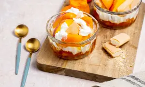 Délicieux dessert printemps : couches de fruits d'abricot, de biscuits à la cuillère et de crème fouettée dans des coupes en verre.