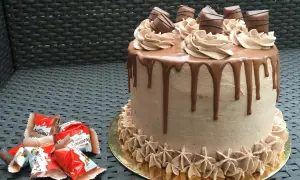 Gâteau au chocolat avec ganache Kinder Bueno, décoré de rosettes et de morceaux de chocolat.