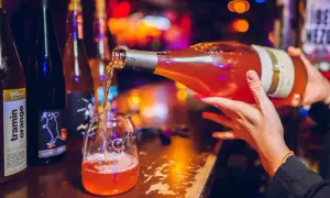 Un verre se remplit d'un vin orange pétillant, promesse d'un moment convivial. Le meilleur vin orange pour une soirée réussie.
