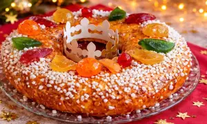 Gâteau des Rois orné de fruits confits et d'une couronne en papier, prêt à être dégusté. Une belle idée pour une recette de gâteau des rois festive.