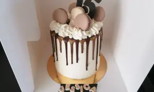 Gâteau drip cake blanc orné de macarons, de chantilly et du chiffre 15. Un délice pour les 15 ans de Jessica.