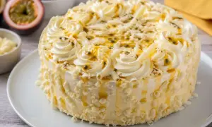 Un délicieux gâteau blanc orné de crème fouettée, de fruits de la passion et de copeaux de chocolat blanc.