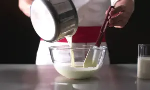Un chef verse un liquide crémeux dans un bol, préparant une délicieuse namelaka vanille.