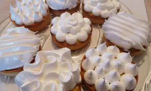 Plateau de tartelettes garnies de crème au citron et couronnées de meringue italienne, une œuvre de conservation gourmande.
