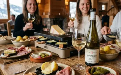 Ambiance chaleureuse autour d'une raclette fumante, accompagnée de pommes de terre, charcuterie et d'un verre de vin blanc, peut-être un Pouilly-Fumé pour sublimer ce moment gourmand.