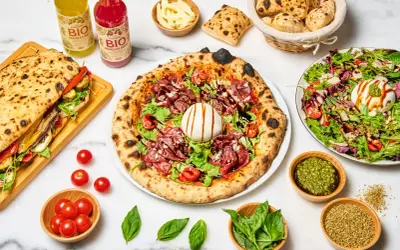 Une pizza savoureuse, un sandwich garni, une salade fraîche et des boissons. Quel vin avec pizza ? Un repas italien parfait pour partager.