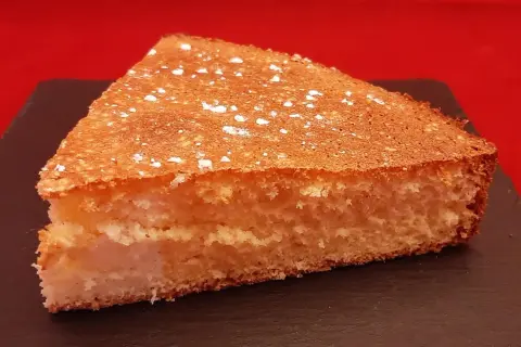 Tranche de gâteau de Savoie aérien, saupoudrée de sucre glace. Une recette facile avec fécule pour un dessert léger.