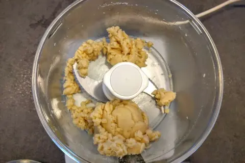 Pâte d'amande maison dans un robot culinaire, prête à être façonnée en délicieuses friandises.