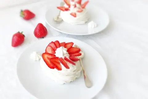Deux pavlovas ornés de fraises et de crème fouettée, une touche de curd mangue passion pour l'exotisme.