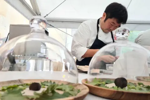 Chef prépare des mets délicats sous cloche, peut-être inspirés par le vignoble de Meursault.