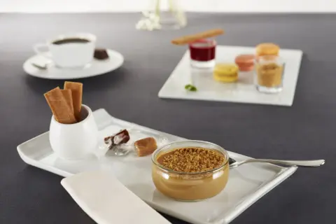Un café gourmand avec diverses mignardises : crème dessert, macarons, biscuits, chocolats. Parfaites pour des recettes de mignardises pour café gourmand.