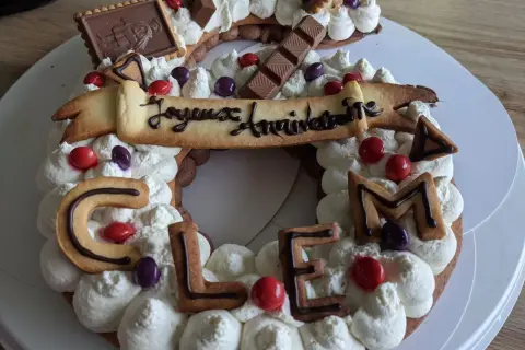 Gâteau décoré de crème fouettée, biscuits en forme de lettres formant "CLEM", chocolats et bonbons. Quelle crème pour recouvrir un gâteau, celle-ci est parfaite !