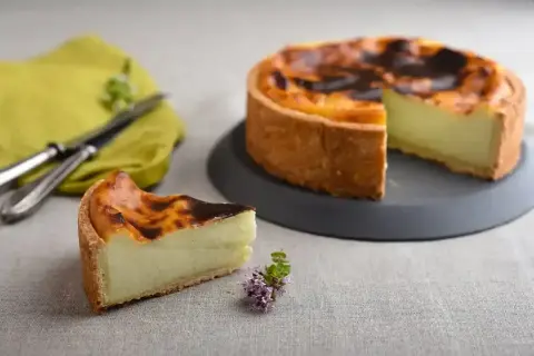 Un flan pâtissier onctueux sur une pâte feuilletée ou brisée dorée, avec une part coupée. Un délice à déguster !