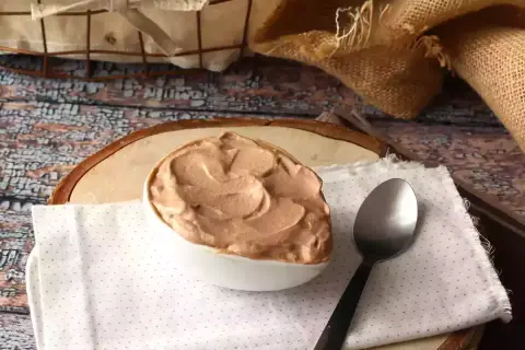 Une cuillère attend patiemment à côté d'un bol rempli d'une onctueuse ganache Nutella, prête à être dégustée.