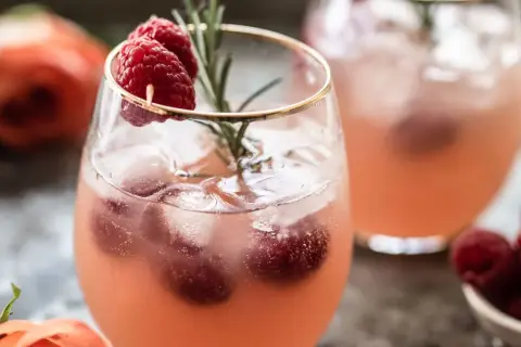 Un délicieux cocktail sans alcool Saint-Valentin, garni de framboises fraîches et d'une touche de romarin. Parfait pour célébrer l'amour !