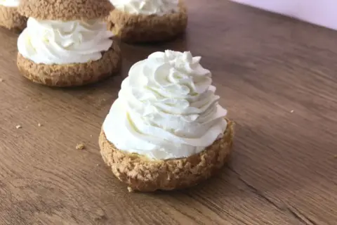 Choux garnis d'une généreuse crème mascarpone vanille, prêts à être dégustés sur fond de bois.