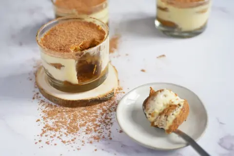 Délicieux tiramisu, un dessert sans cuisson, servi dans des verres, saupoudré de cacao. Une cuillère en est prête à être dégustée.