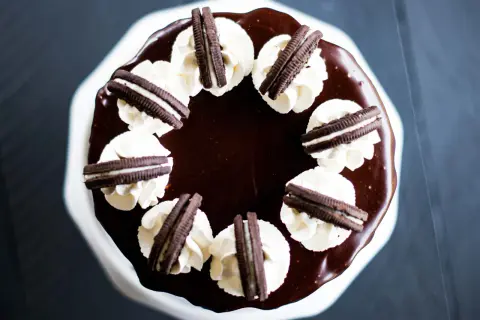 Gâteau au chocolat glacé, décoré de crème fouettée et de biscuits Oreo. Un délice pour les amateurs de layer cake Oreo.