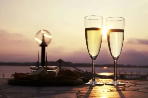 Deux flûtes de ratafia de Champagne pétillant, servies avec des amuse-bouches au coucher du soleil. Parfait pour savoir comment le boire.