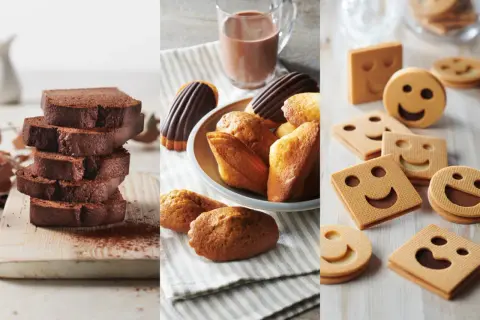 Tranches de cake au chocolat, madeleines et biscuits souriants. Parfait pour une recette goûter gourmande.