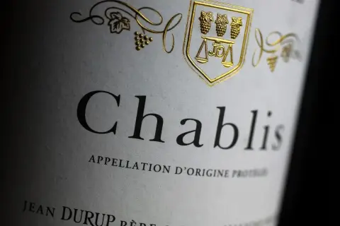Étiquette d'un Chablis, vin blanc sec ou moelleux, avec un blason doré orné de grappes de raisin.