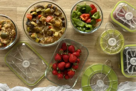 Préparation pour le batch cooking du goûter : ratatouille, poivrons coupés, fraises et autres ingrédients dans des boîtes hermétiques.