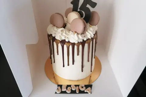 Gâteau drip cake blanc orné de macarons, de chantilly et du chiffre 15. Un délice pour les 15 ans de Jessica.