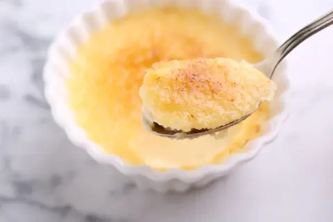 Une cuillère de semoule au lait au four, dorée et caramélisée, prête à être dégustée.