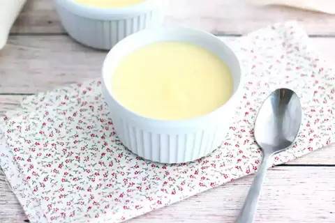 Deux ramequins de crème dessert rapide sans cuisson sur une serviette fleurie, avec une cuillère.
