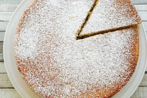 Un délicieux victoria sponge cake, saupoudré de sucre glace, avec une part déjà coupée. Parfait pour le thé !